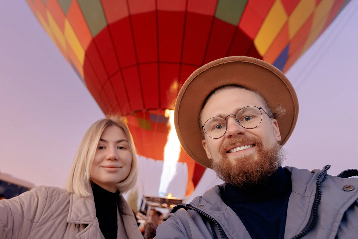 Happy man hipster making selfie photo on phone background hot air balloons in Cappadocia.