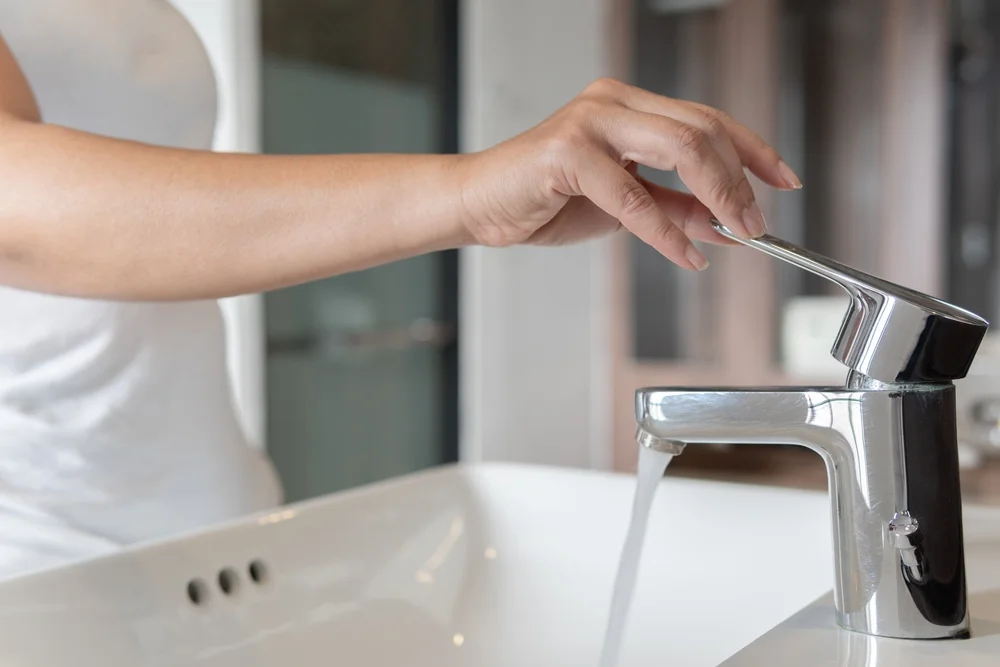 woman turning on faucet