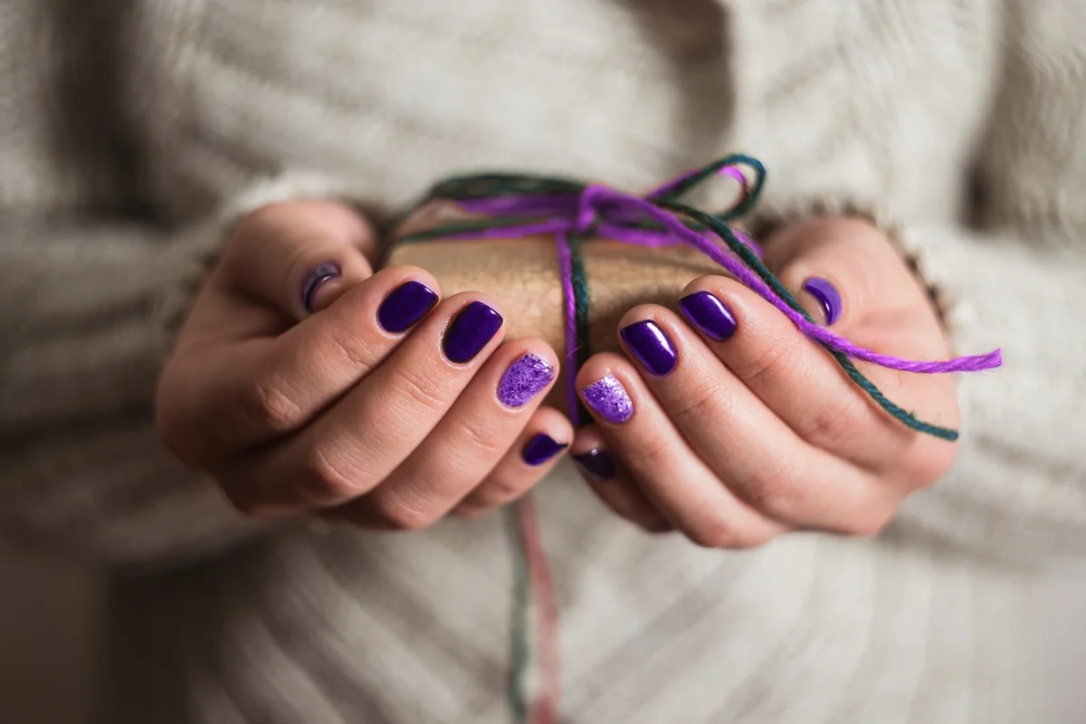 hands holding a decorative gift, ornaments over a wooden background