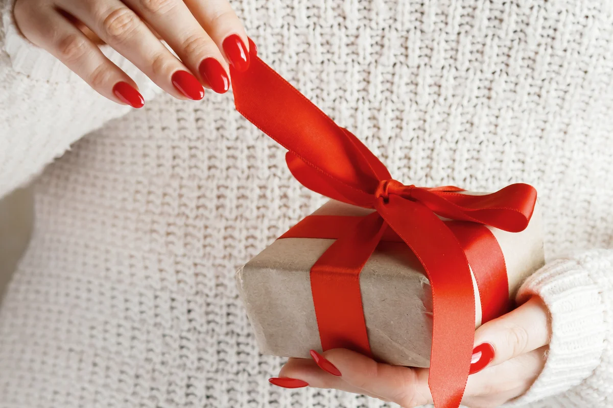 Beautiful gift in hands of young woman with red manicure