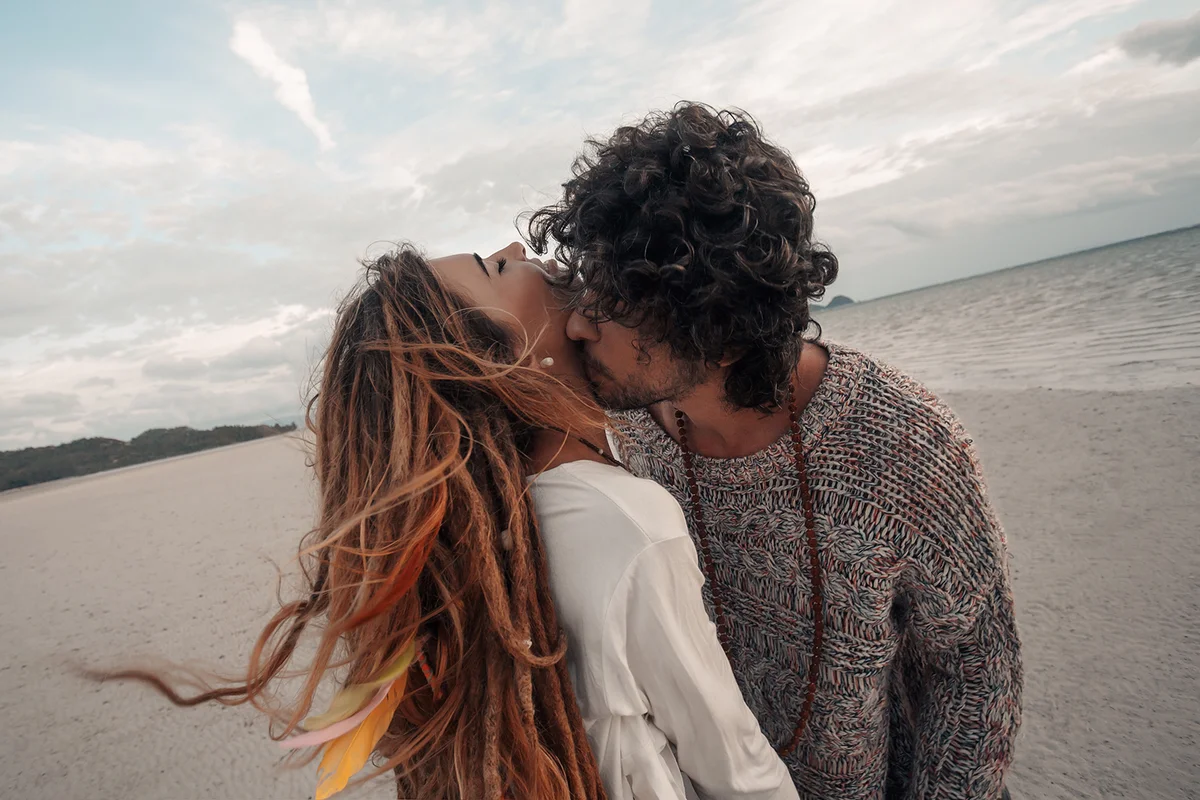 beautiful young couple kissing on beach at sunset