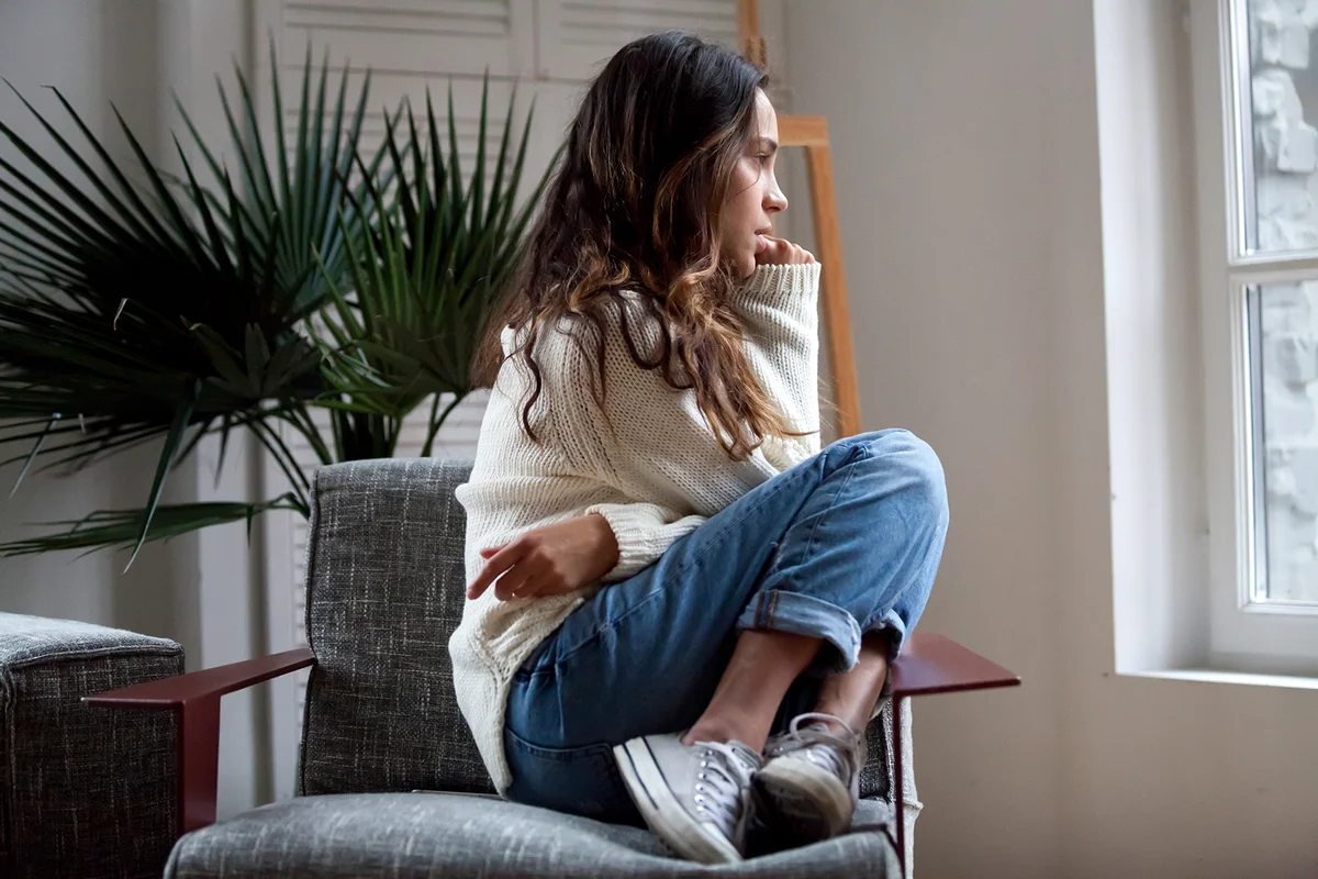 Sad thoughtful woman sits on chair feels depressed