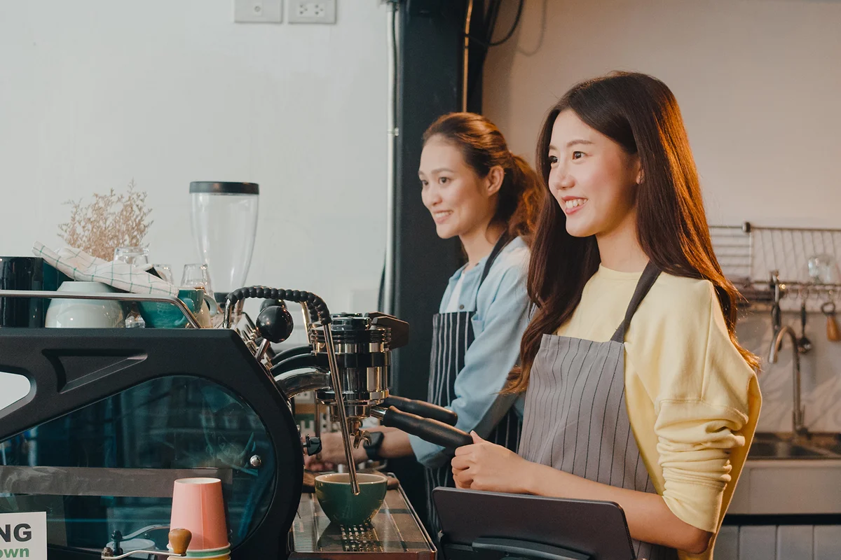 young lady barista working with coffee machine in coffee shop