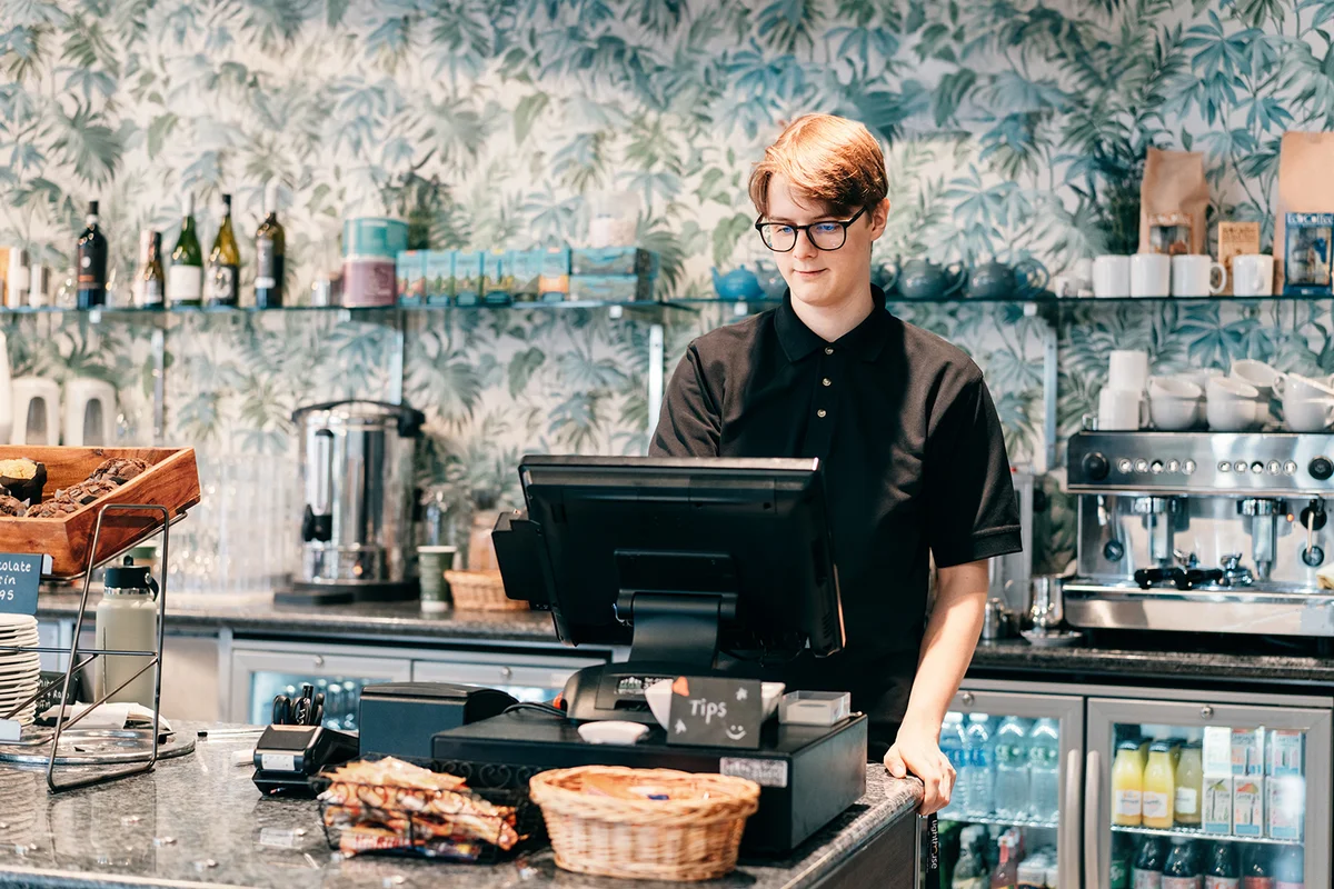 Young waiter serving customer at cash point in cafe