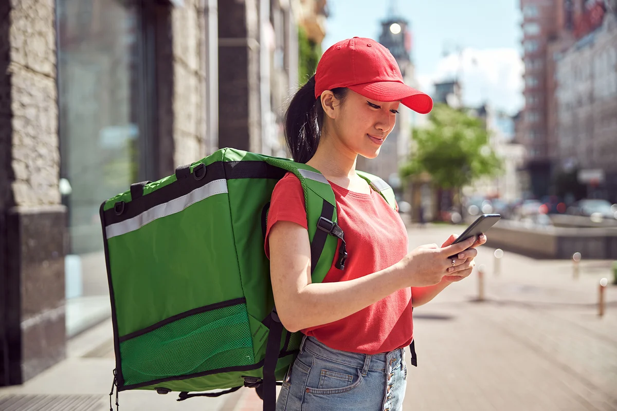 student delivering food through city using mobile phone