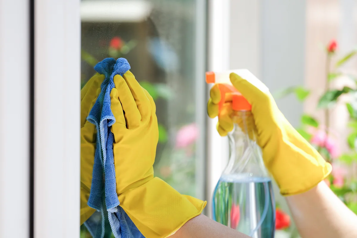 woman applying detergent spray and rag for cleaning window outside