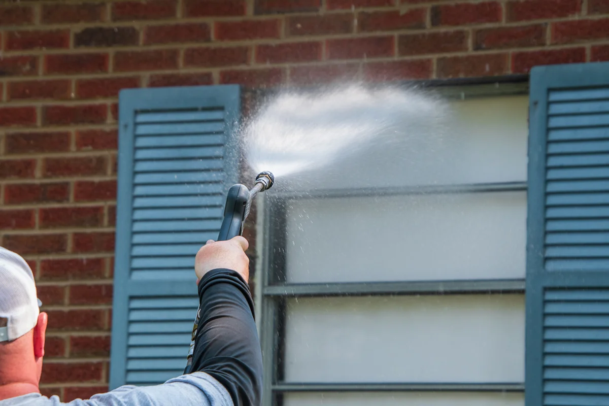 Arm and hand holding a sprayer aimed at a window