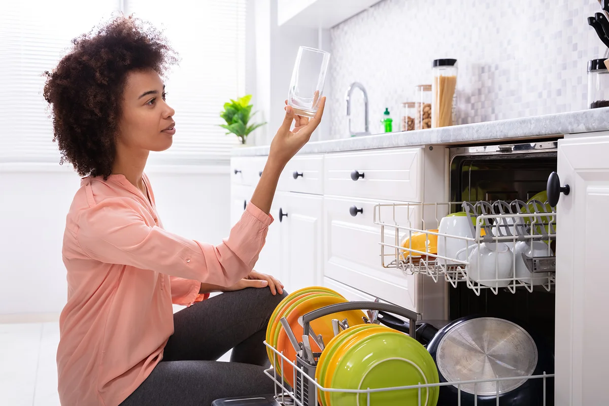 Woman Checking Washed Transparent Drinking Glass Near The Dishwasher