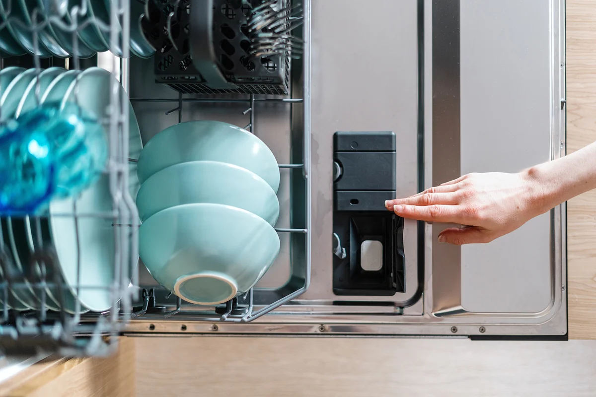 opened dishwasher machine with plastic detergent compartment and chemical tablet