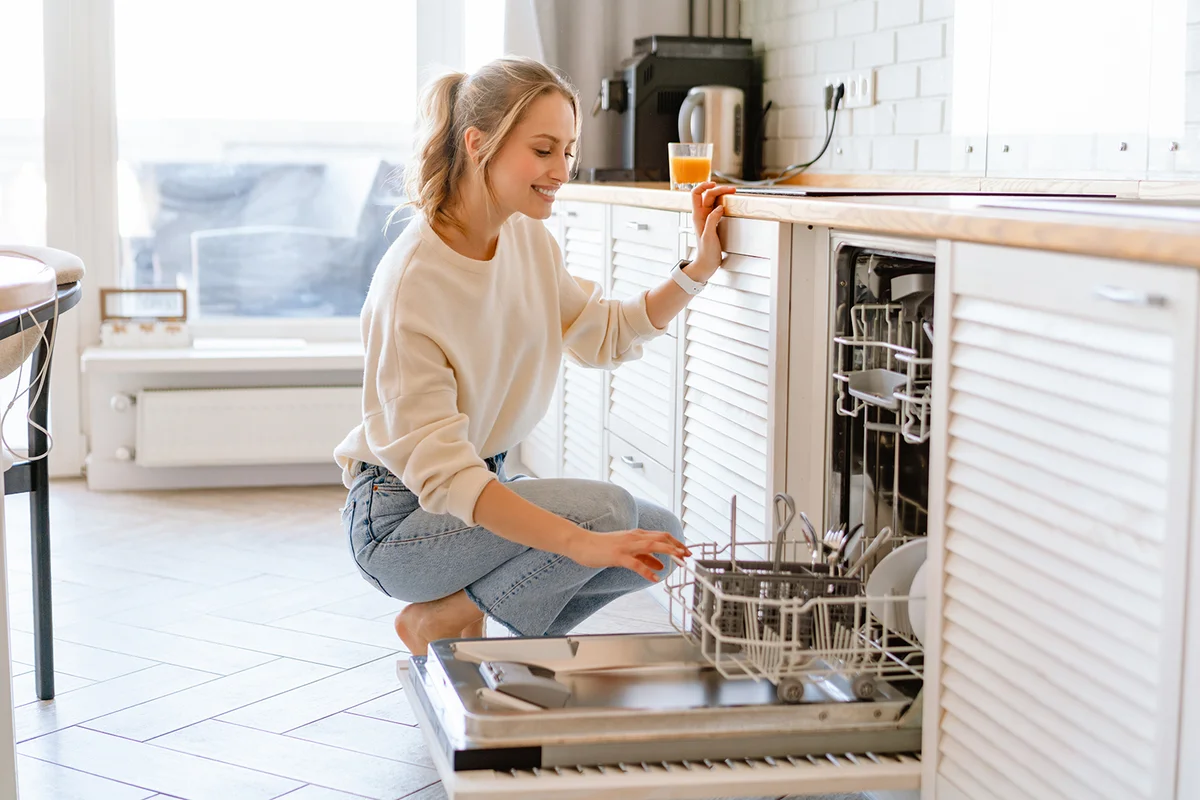 woman putting dishes in the dishwasher at home