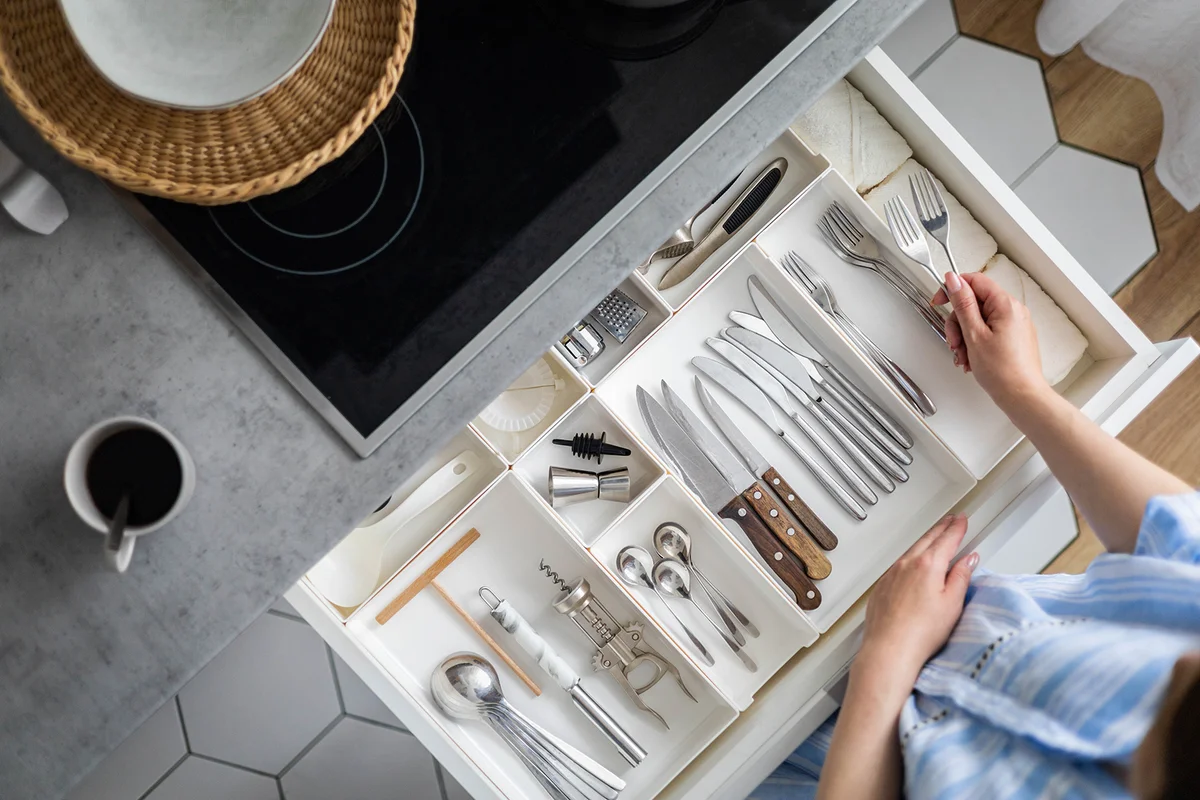 woman hands tidying up cutlery in drawer general cleaning at kitchen