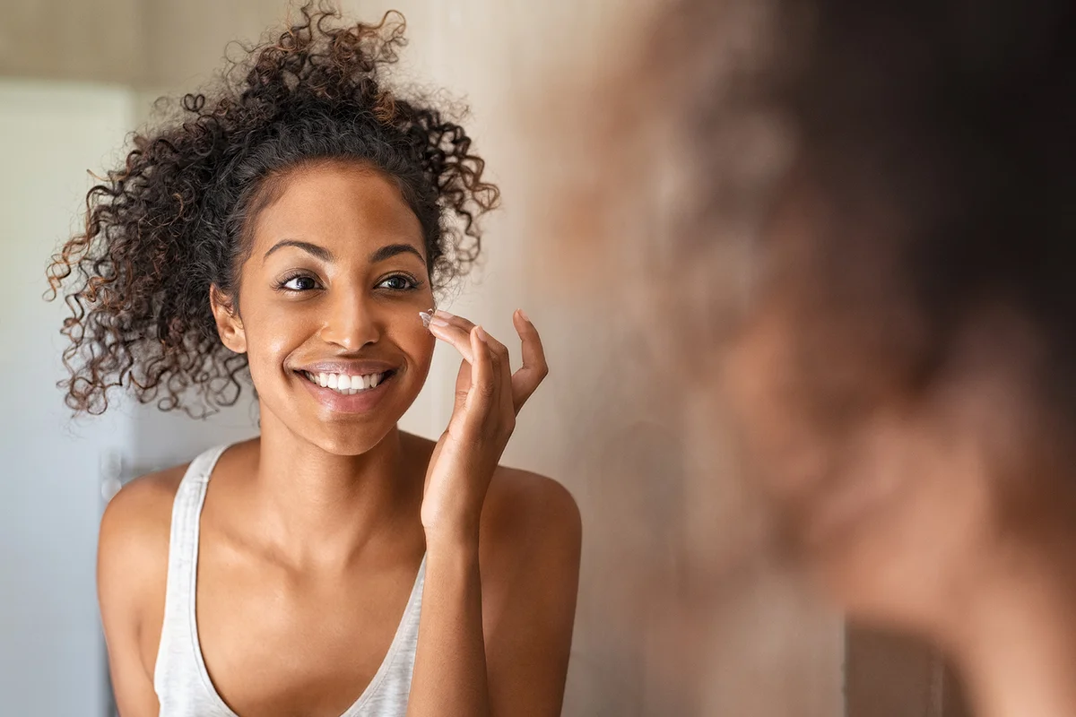 woman applying moisturising cream on cheeck
