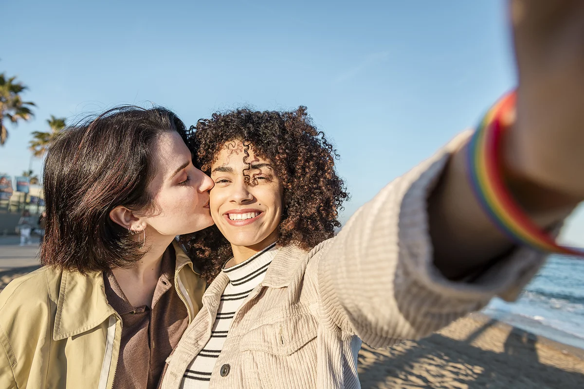selfie photo of young multiracial couple of beautiful lovely girls smiling and kissing,