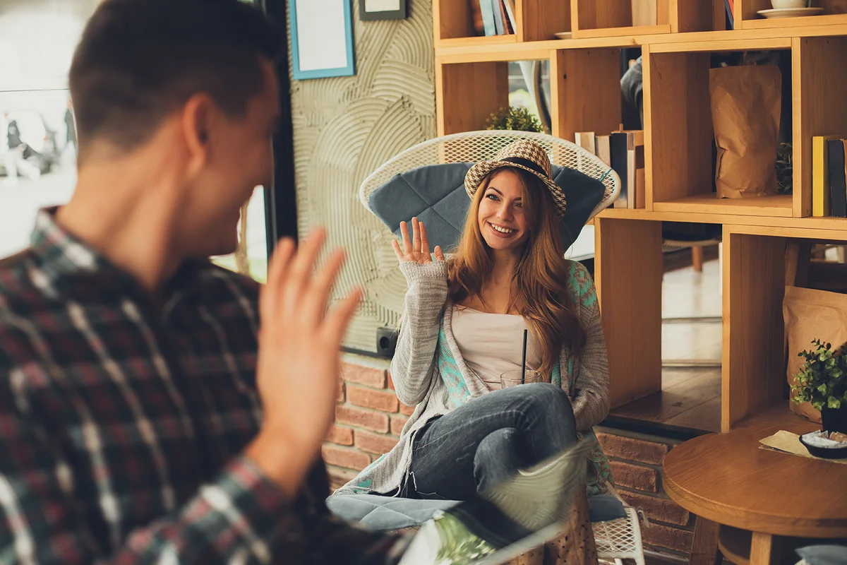 Young man and woman say hi each other in cafe flirting situation