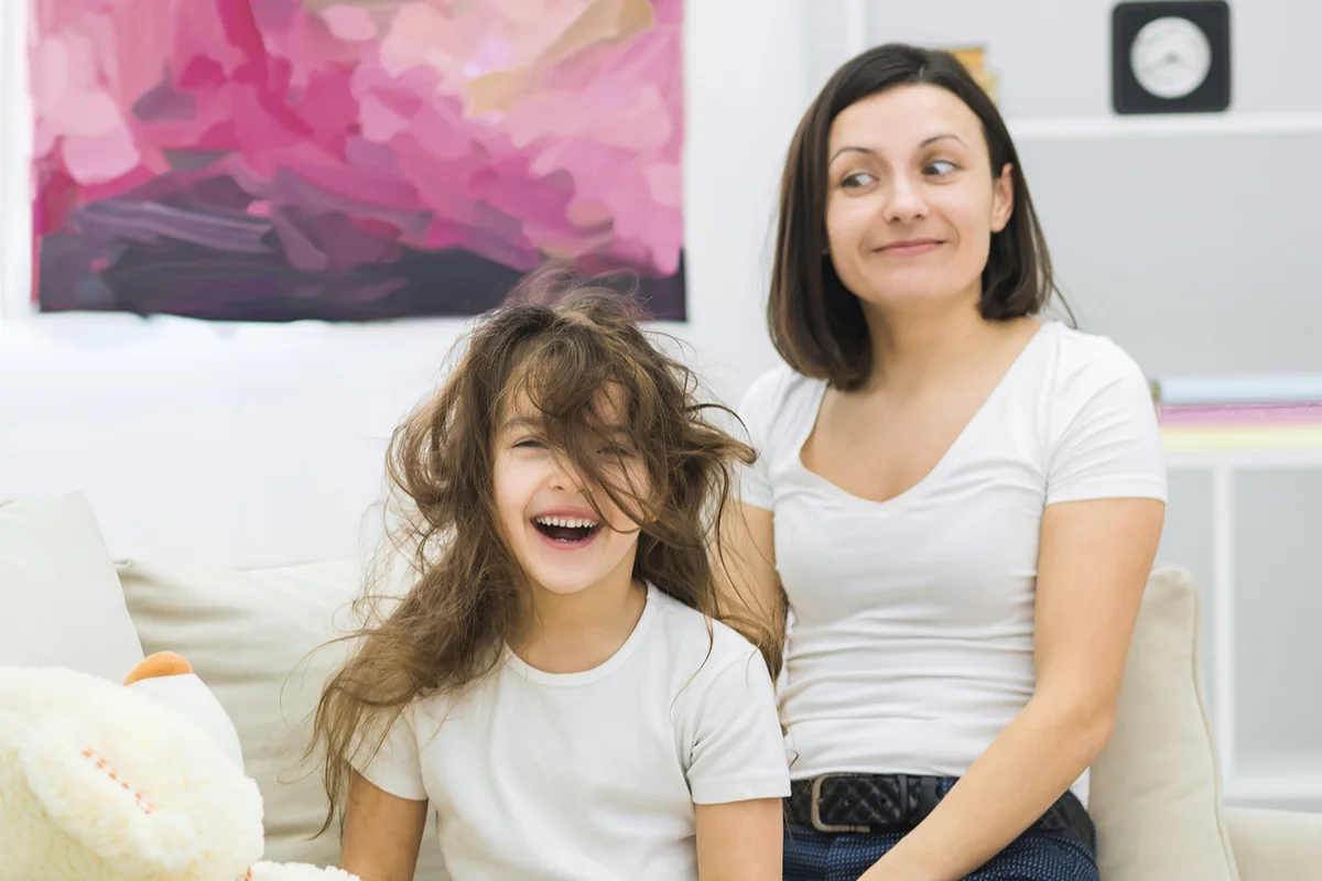 Photo of little girl with messy hair and her mother beside.