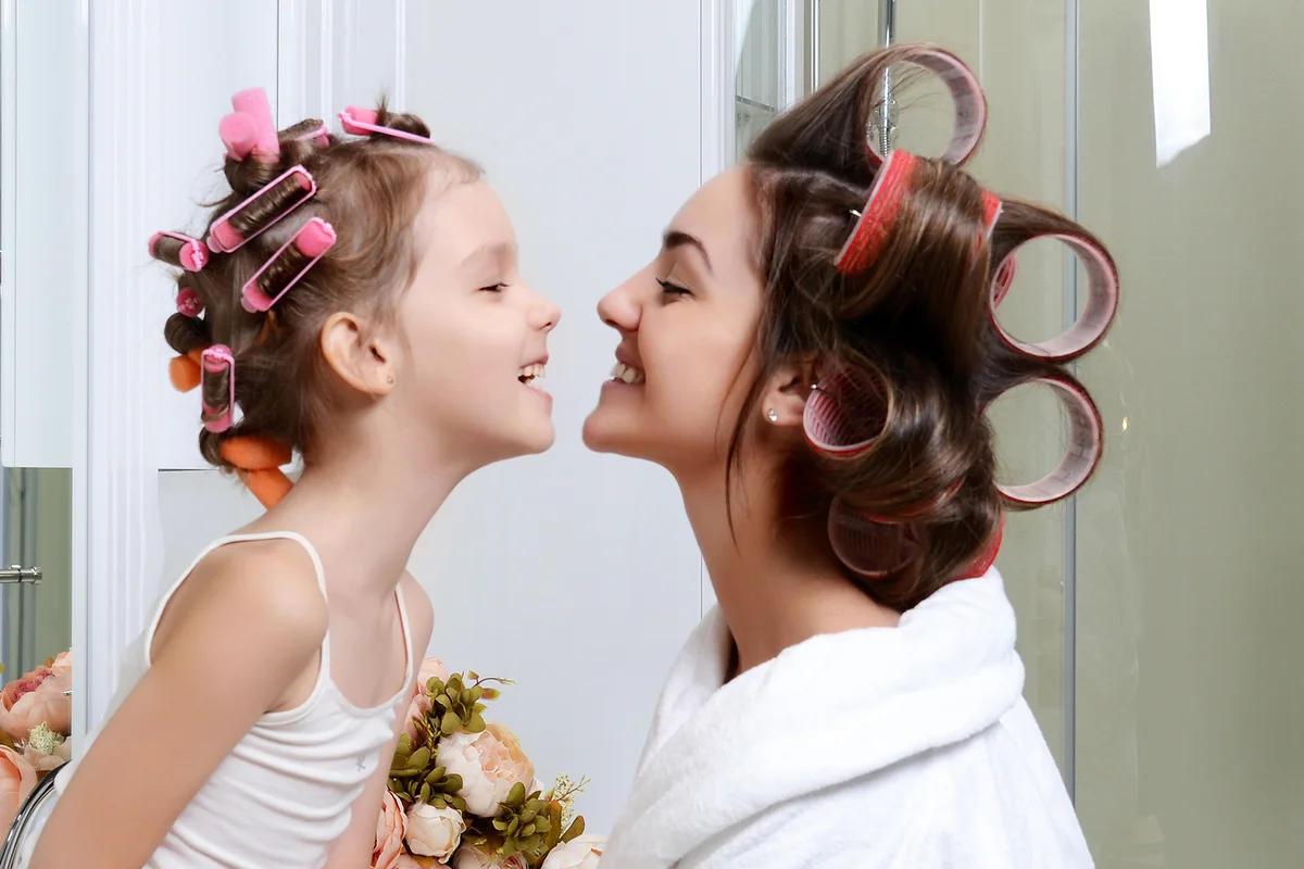 Young mother and daughter in curlers in a bath room