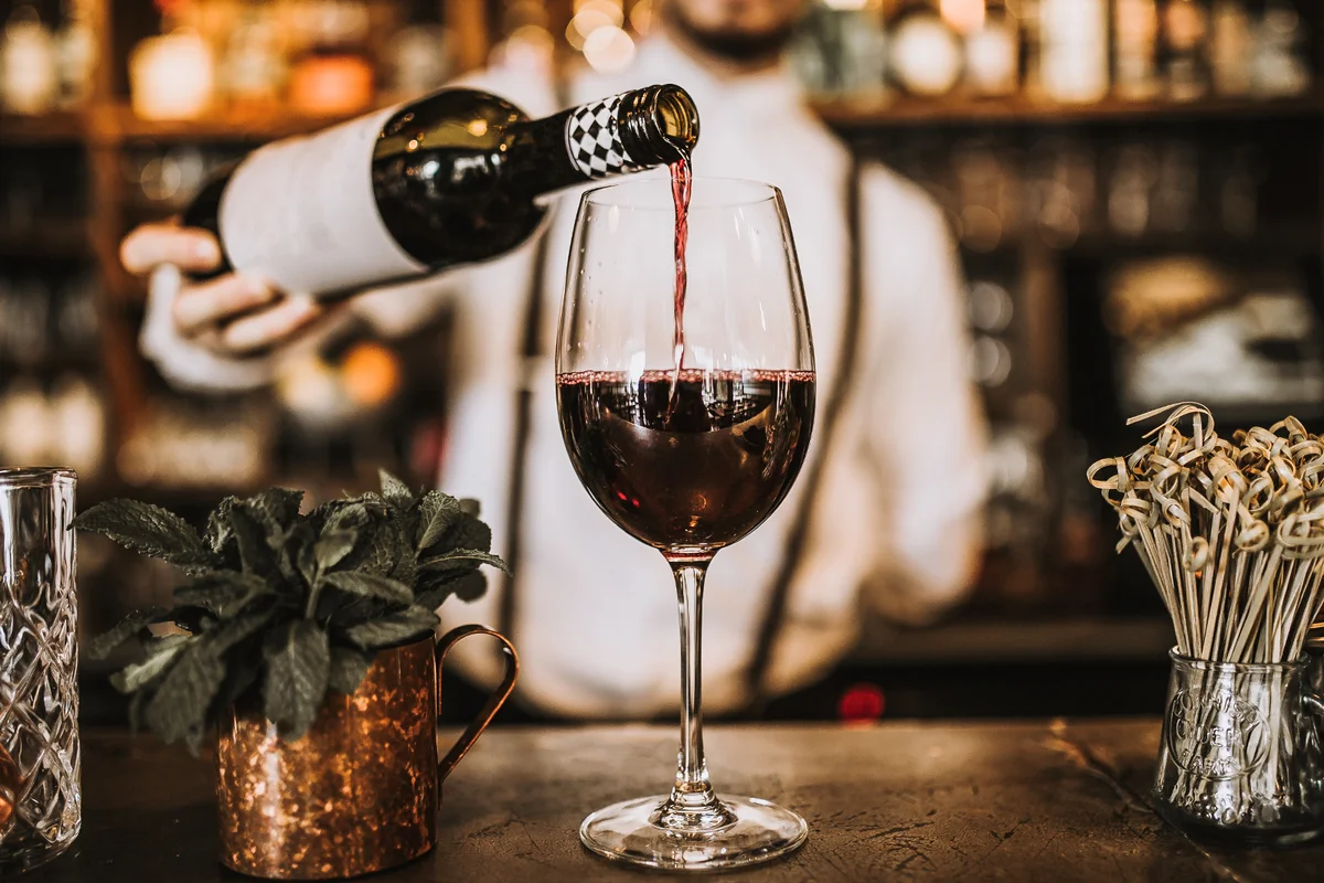 Bartender pouring red wine from a bottle in a wine glass