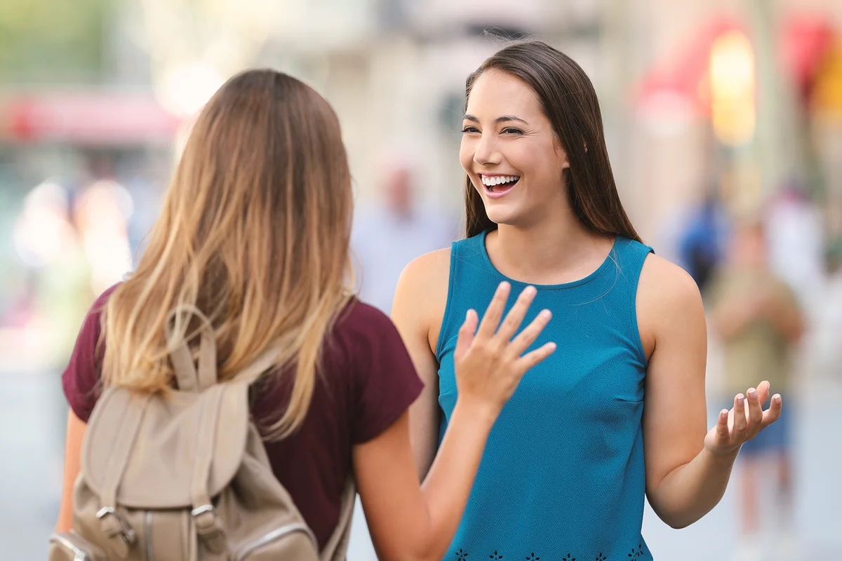 Two happy friends meeting and greeting on the street with a blurred background