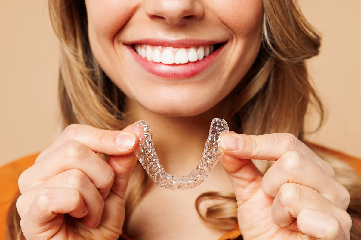 woman holds invisible transparent aligners
