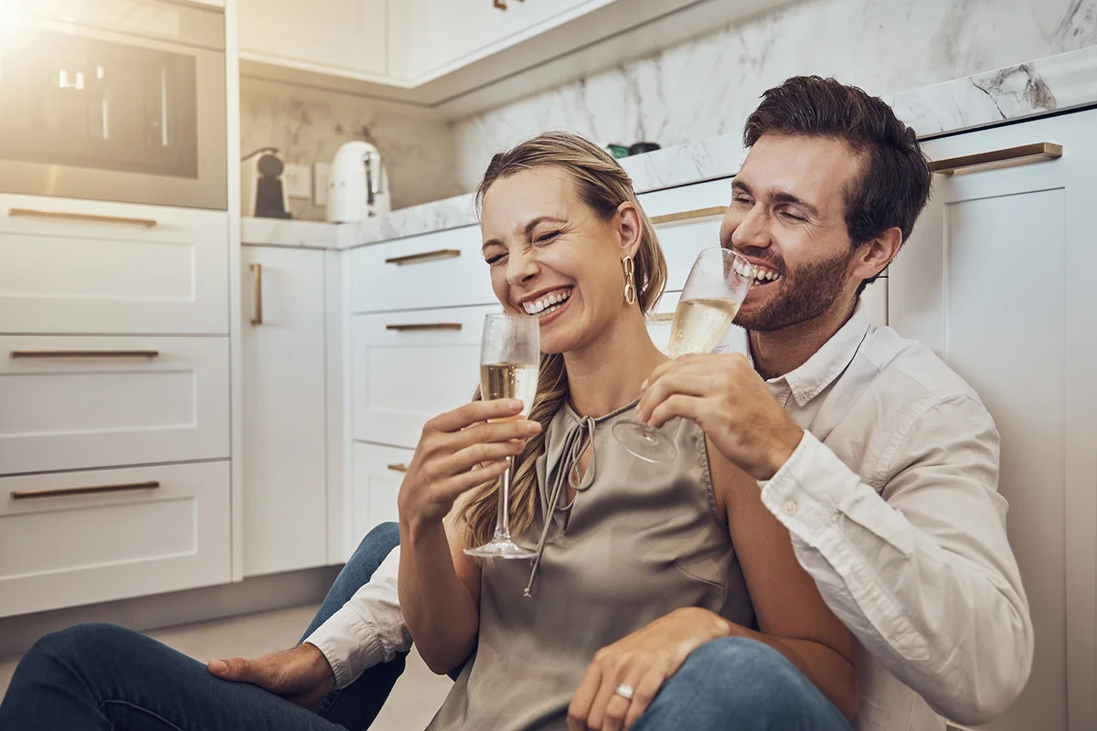 love and couple with champagne in the kitchen for celebration