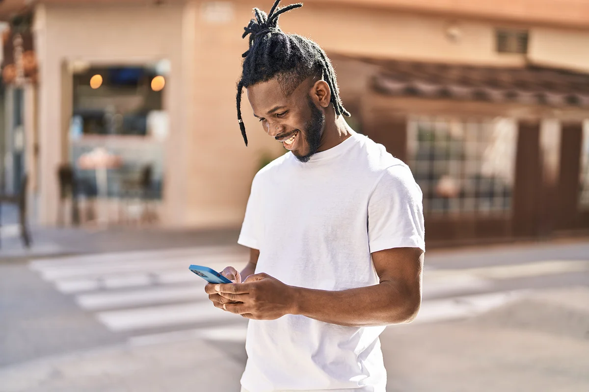 man smiling using smartphone at street