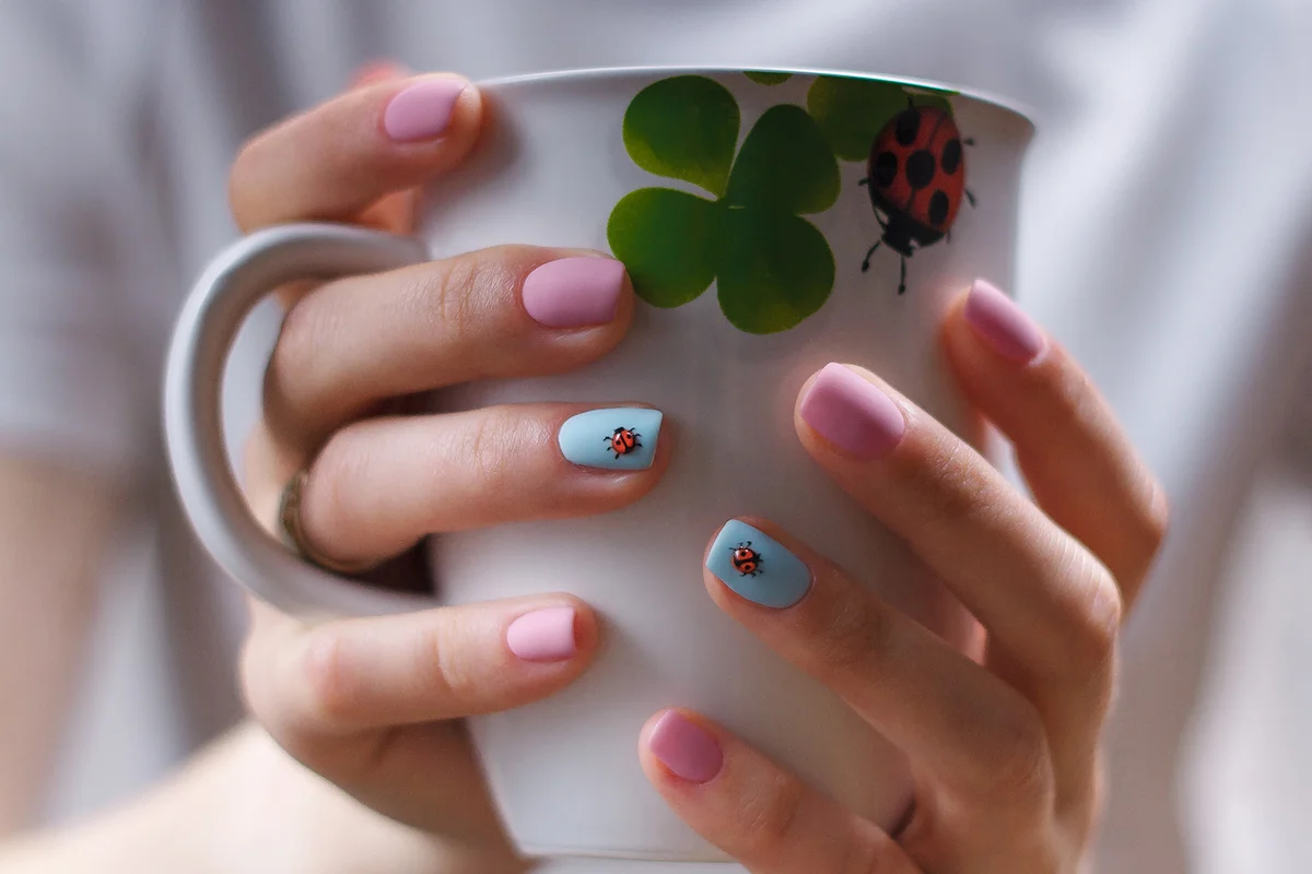 Girlish manicure with volumetric ladybugs on pink and blue fingernails.