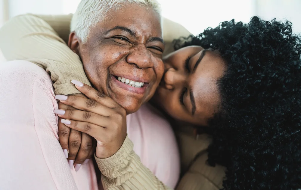 Happy black young woman hugging and kissing her mother