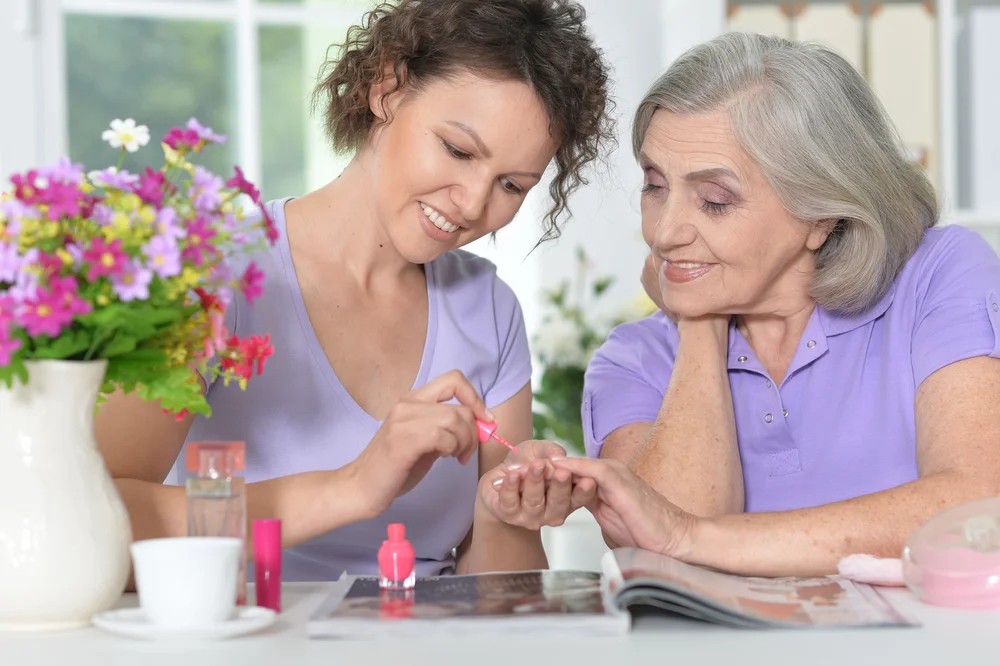 Woman painting her mother's nails at home