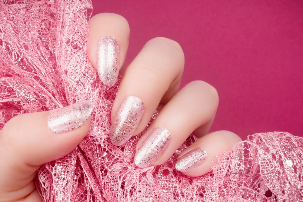 Close-up of a pink glittery manicure on a hot pink background