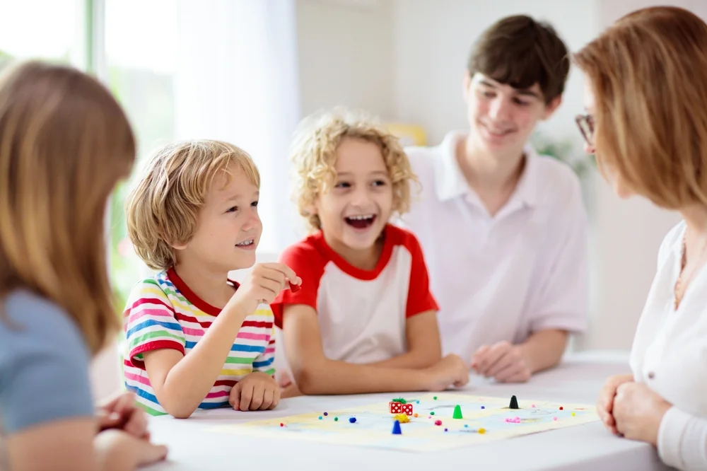 Kids playing a fun board game with their grandma at home