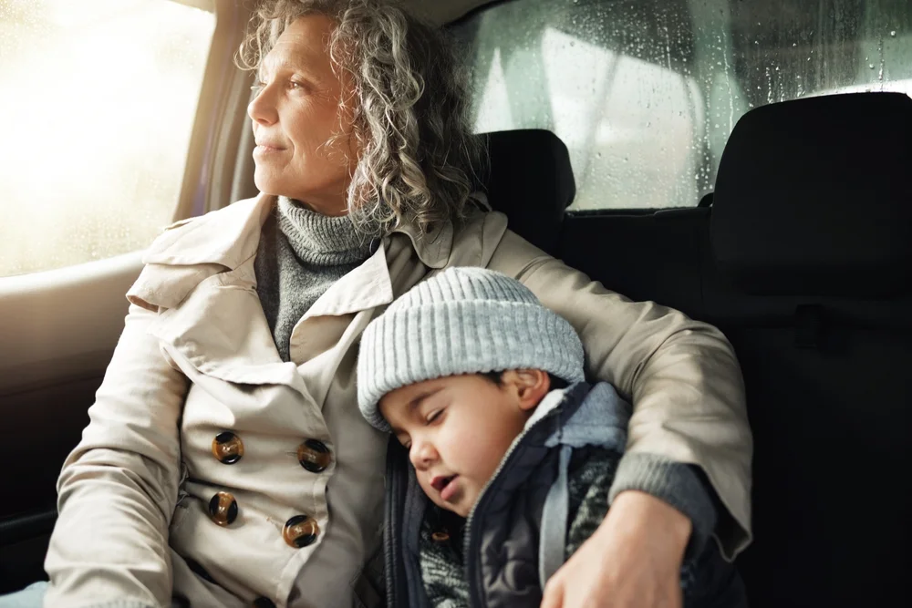 Sleeping child and grandma in the back of the car during a road trip