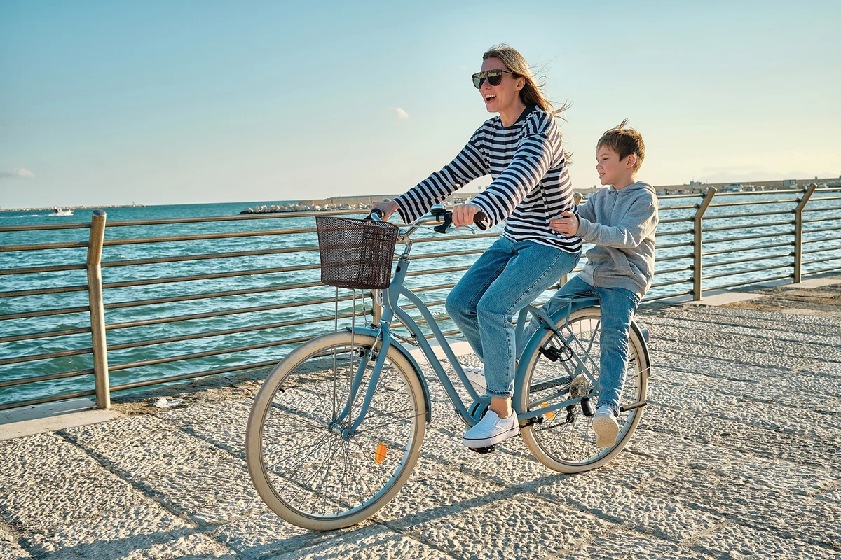 mother and son with bike riding on beach having fun