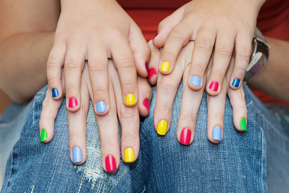 Hands of mother and daughter with colorful manicures
