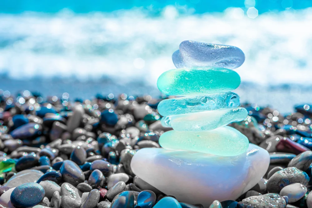 Sea glass stones arranged on the beach with a blurred seascape background.