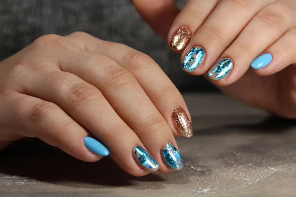 Two hands with a beautiful blue and gold abstract manicure