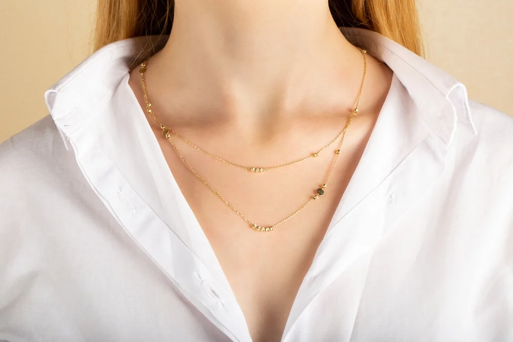 Close-up detail of a young lady's asymmetrical gold necklace