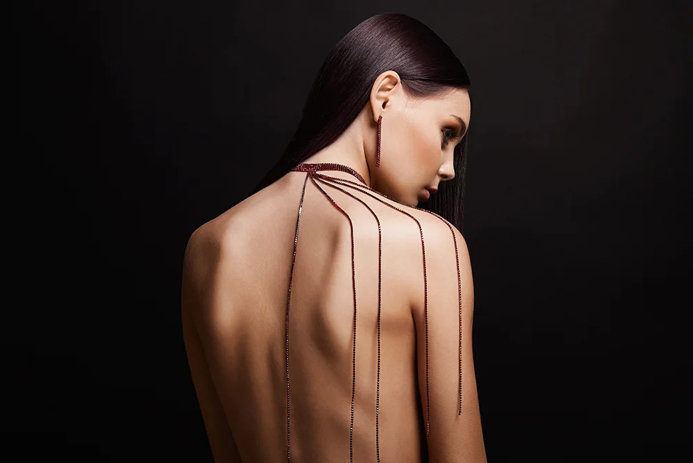 Medium back shot of a model with a body chain in her shoulder and matching earrings