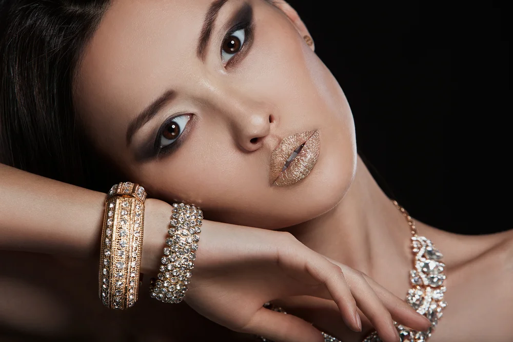Beautiful close-up portrait of an Asian woman with big diamond bracelets and gold lips
