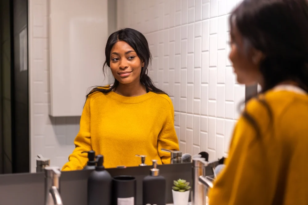 A smiling woman that looks at herself in the mirror