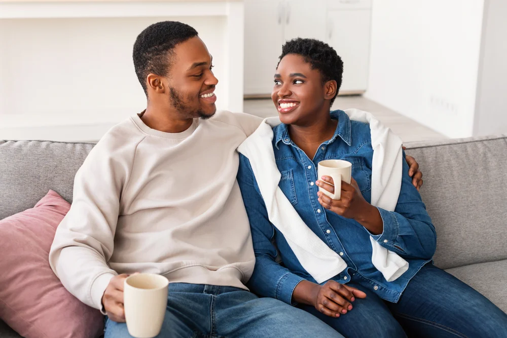 Portrait of smiling couple talking while sitting on the sofa at home