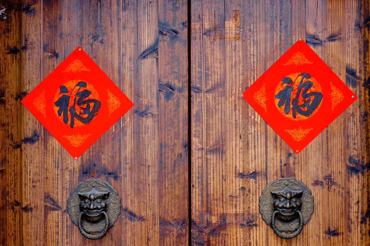 The Handwriting Chinese blessing "Fu" on the wooden door with traditional chinese bronze handle during the Chinese New Year