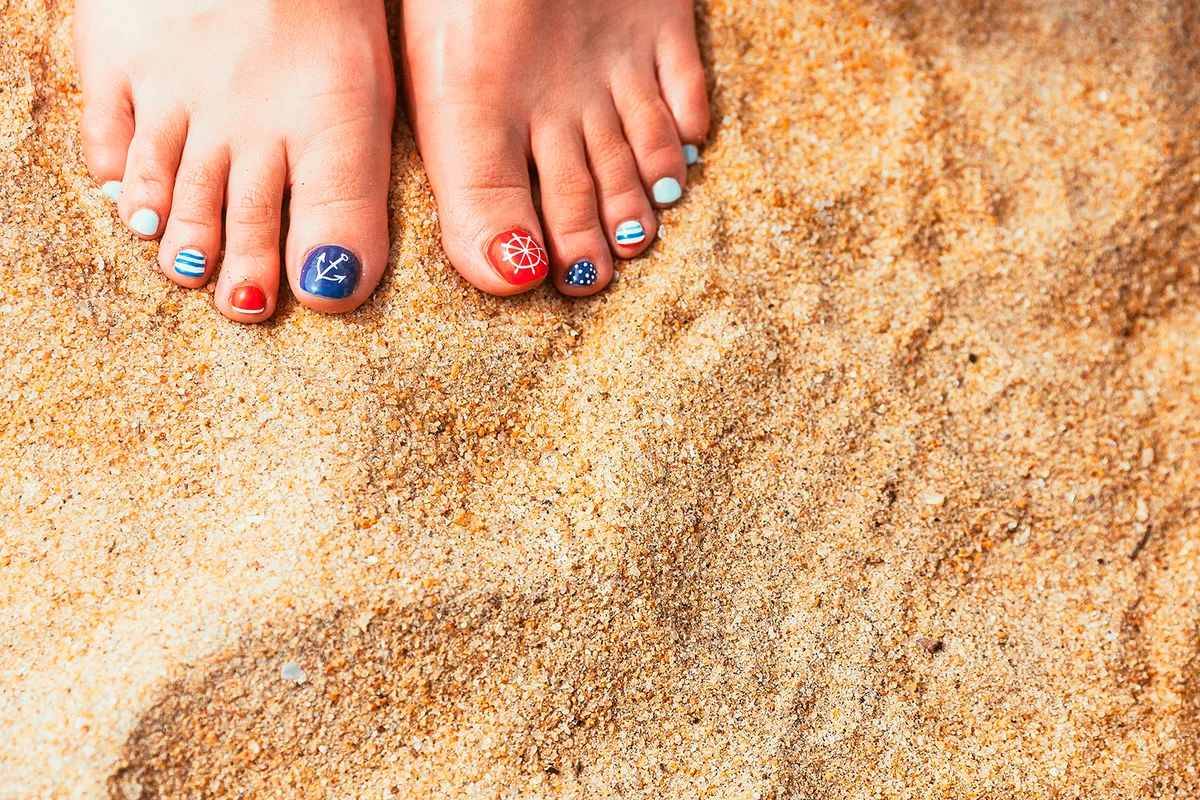 Woman feet with red toenails on natural beach sand