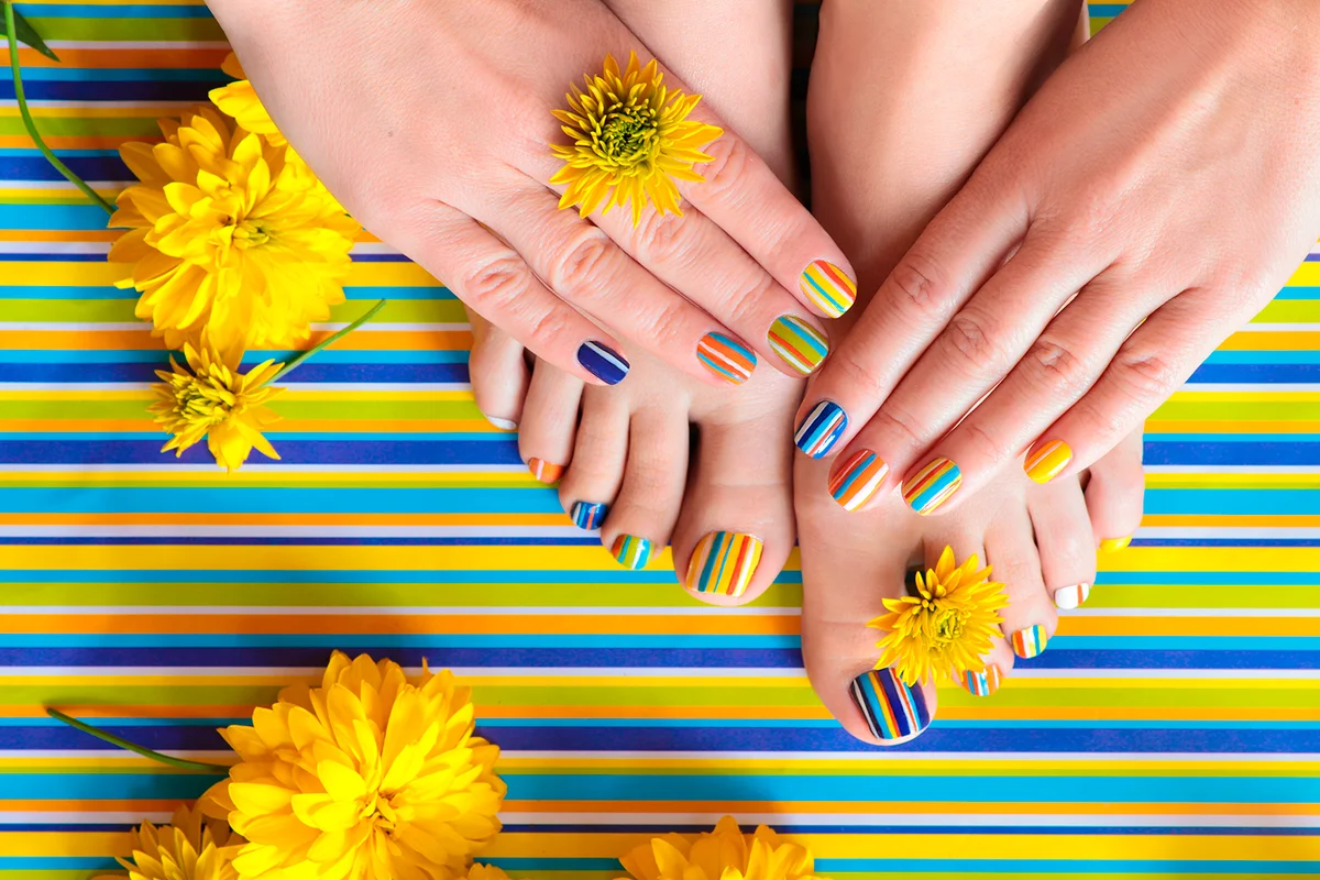 Colorful striped fashion summer pedicures and manicures for women's short nails with yellow flowers.Nail art.