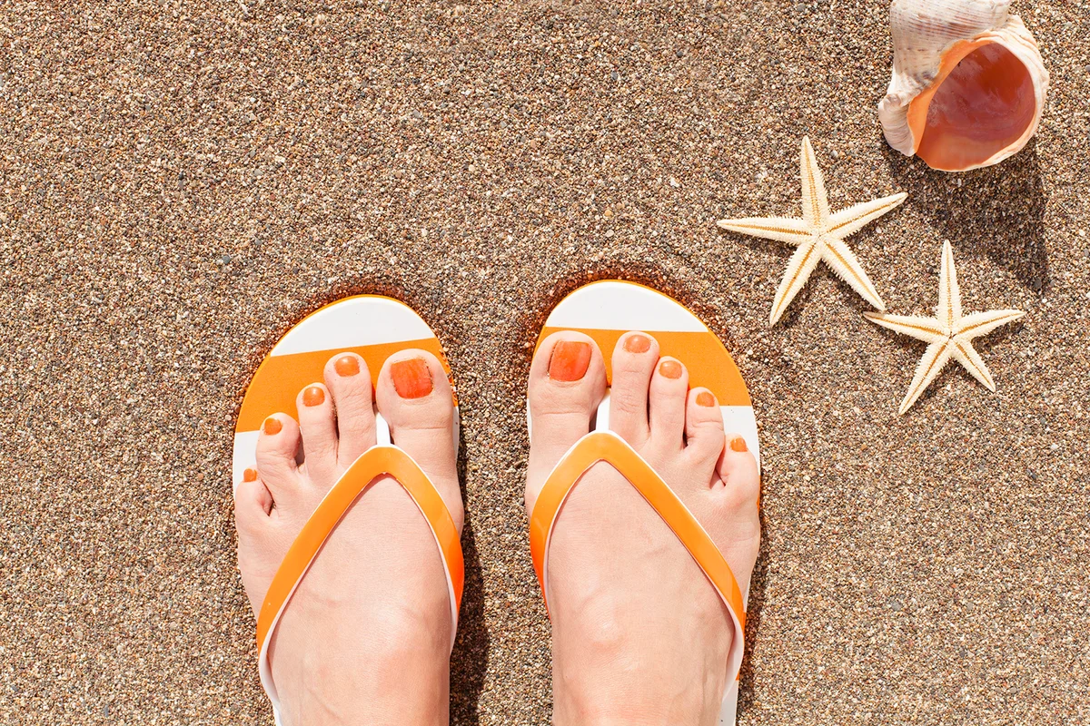Young girl feet in colorful flip-flop sandal on sea beach