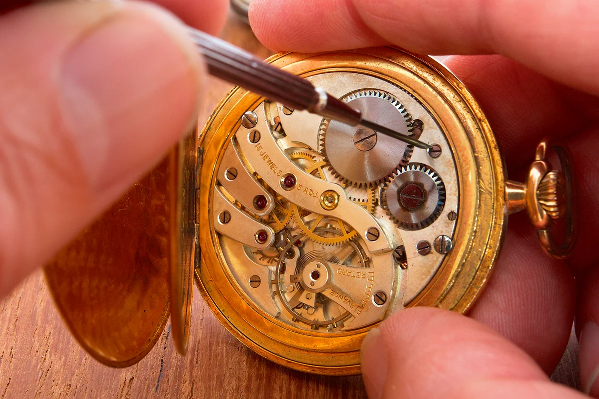 hands that repair an old pocket watch
