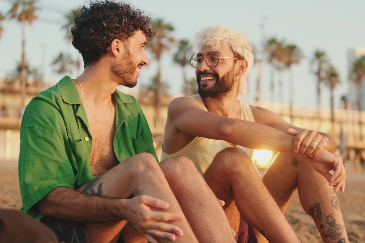 couple talking and laughing while sitting on the beach at dawn