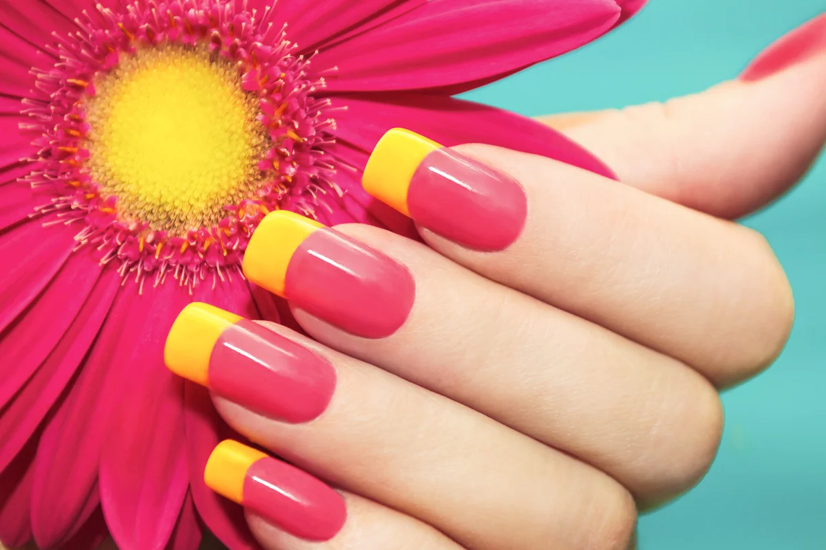 Two-tone manicure with pink and yellow varnish with flower gerbera