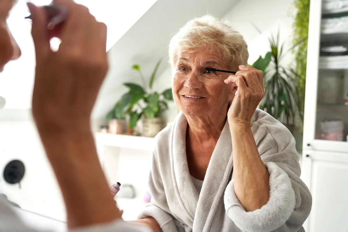 Senior woman doing eye make up in the bathroom