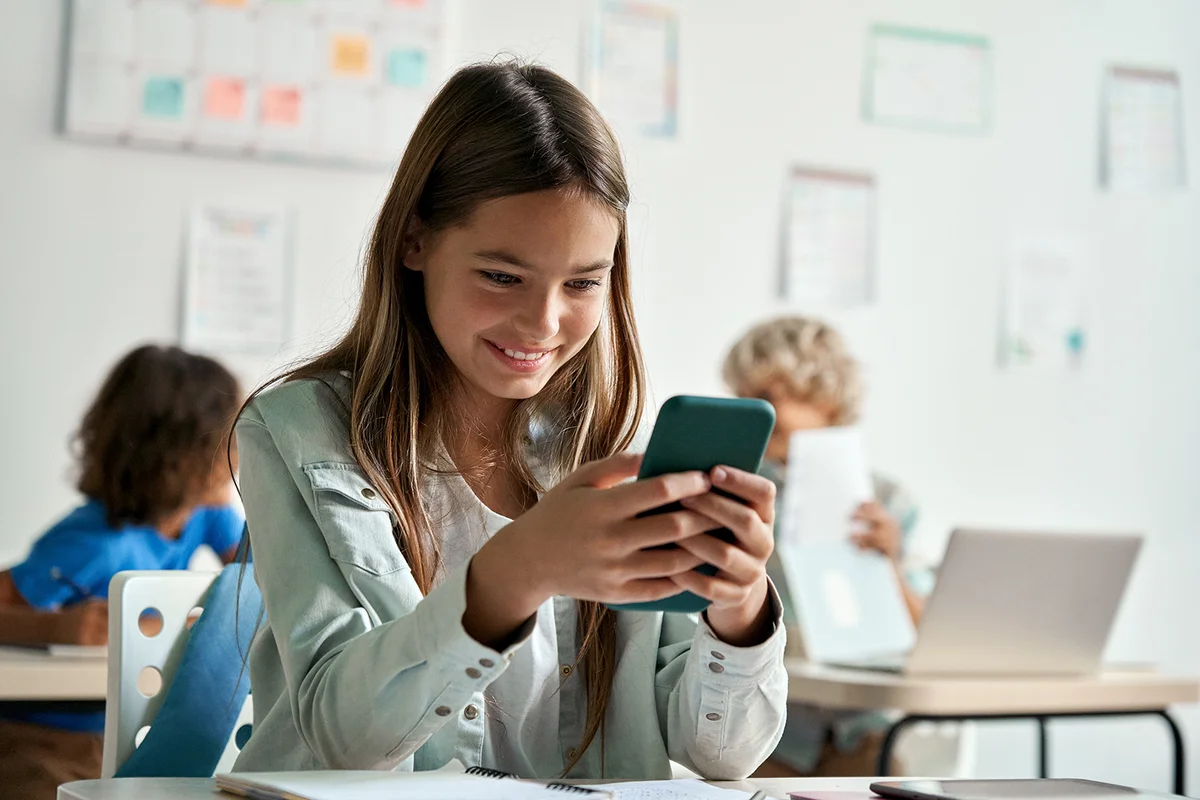Teen girl school student using smartphone in classroom