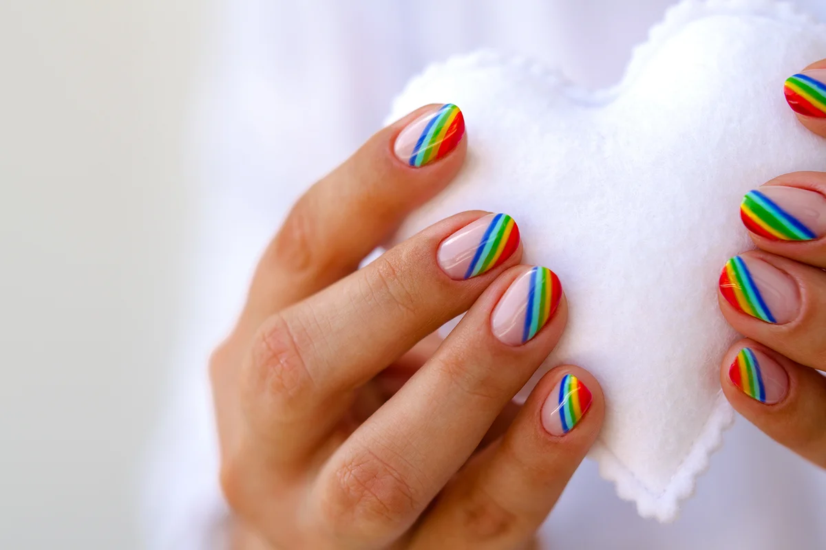 White felted heart in femaile hands with rainbow manicure